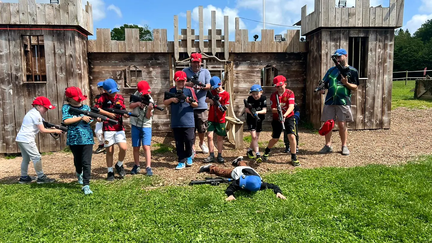 Children and adults in red and blue sensor caps outside the laser tag castle at Escot Park, Devon