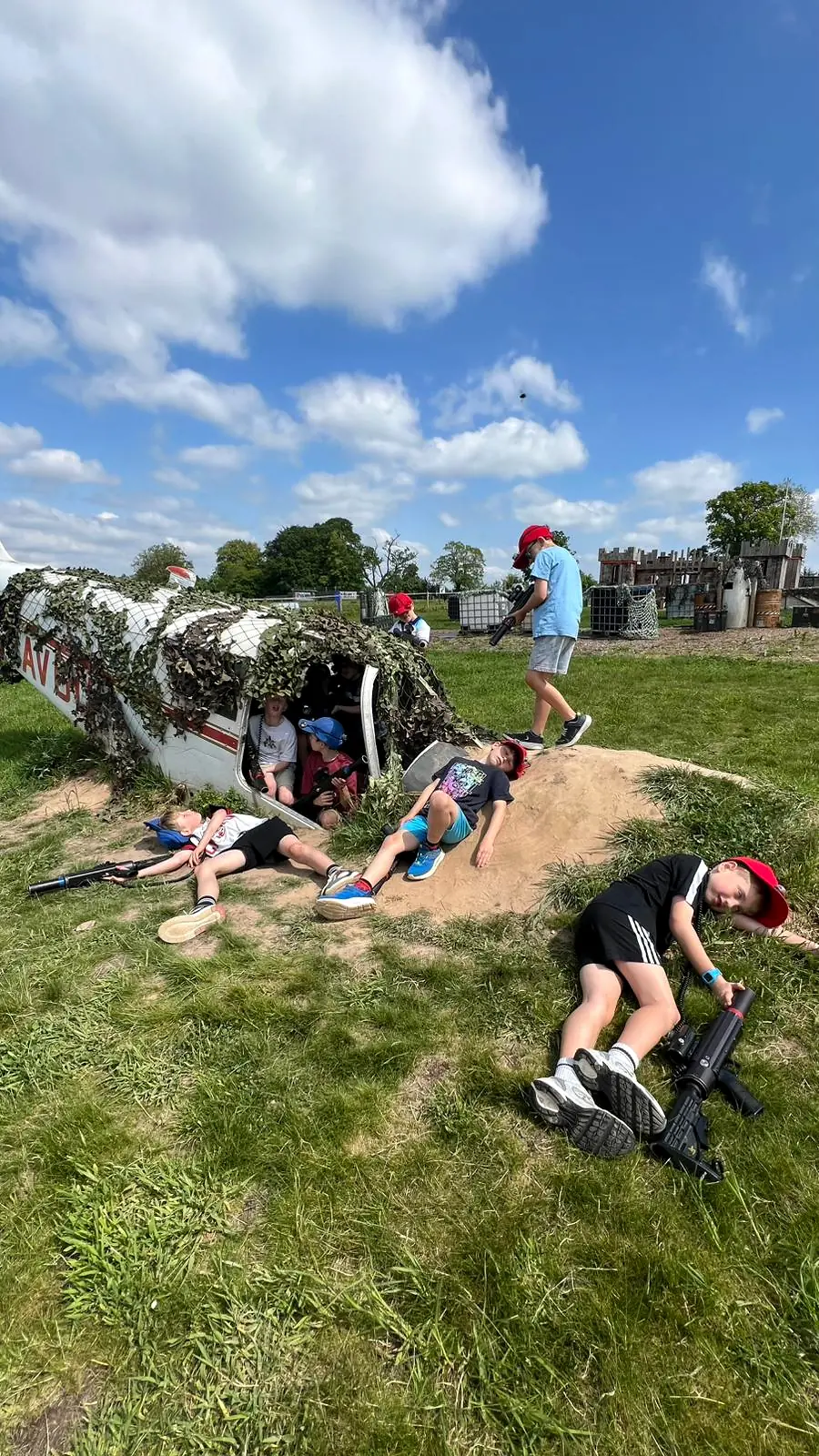 Children posing with laser tag equipment around the aircraft obstacle on the grass arena in Devon