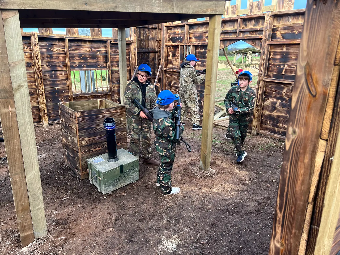 Young laser tag players in camouflage overalls working together inside the timber castle